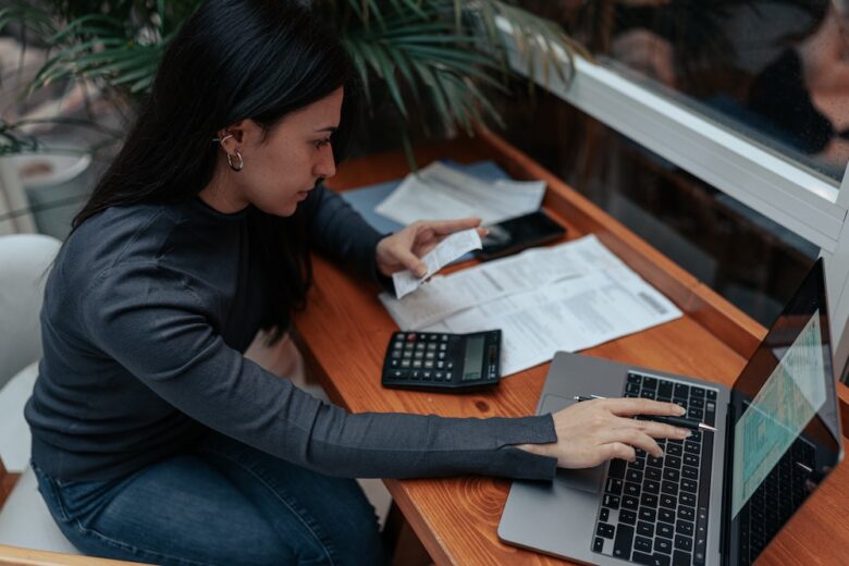 woman calculating her expenses for tax return and typing them into a laptop